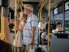 Mehrere Personen fahren in einem Stadtbus; im Vordergrund steht ein älterer Mann mit einem Kind